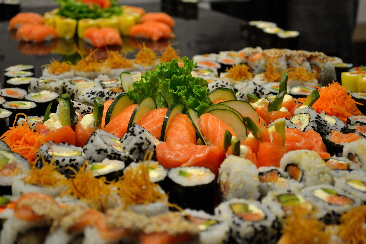 Sushi rolls and salmon sashimi arranged across a dark table