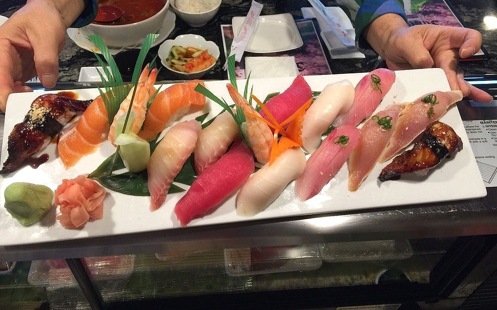 A long white plate of nigiri — salmon, tuna, yellowtail, shrimp and eel — with ginger and wasabi