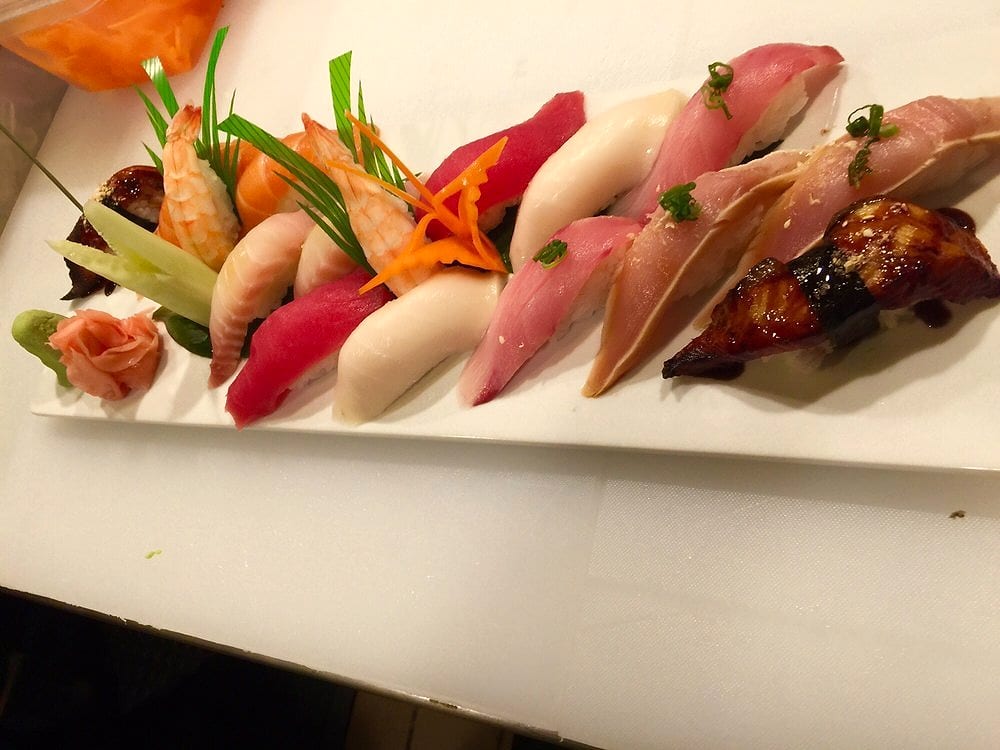 A long plate of nigiri: shrimp, salmon, tuna, white fish, yellowtail and eel, with ginger and wasabi